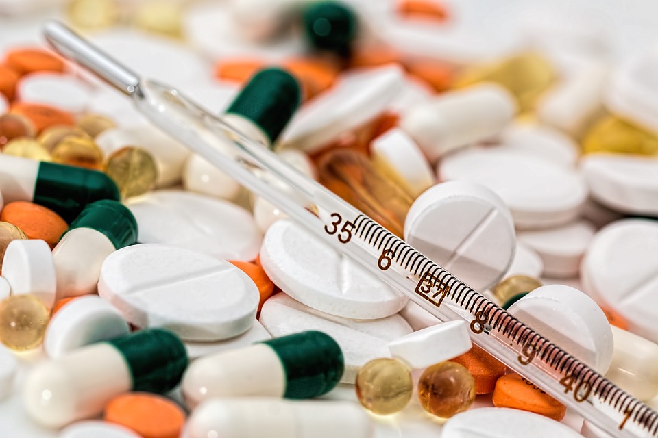 thermometer lying on assortment of prescription pills