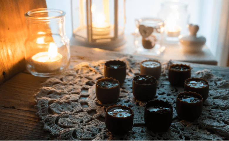 table lit with candle light and nine chocolate peanut butter cup vegan cannabis edibles