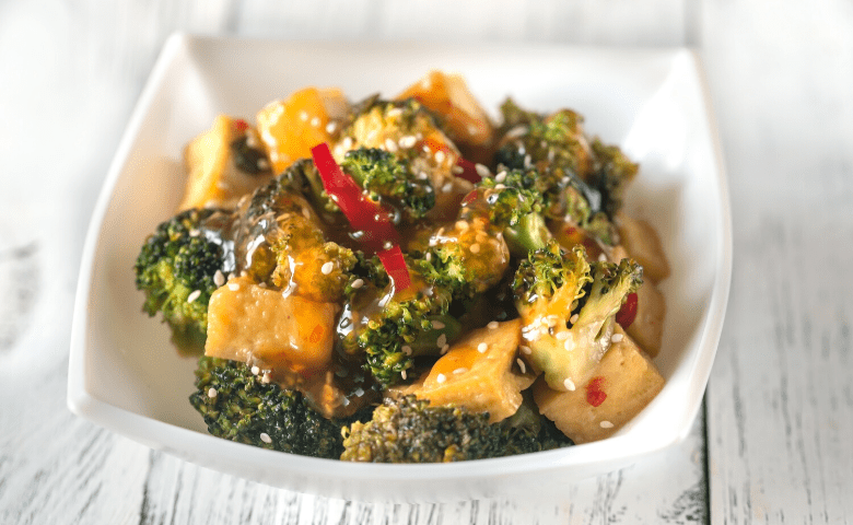 vegan cannabis stri fry with broccoli, tofu, peppers, and sauce in white square bowl