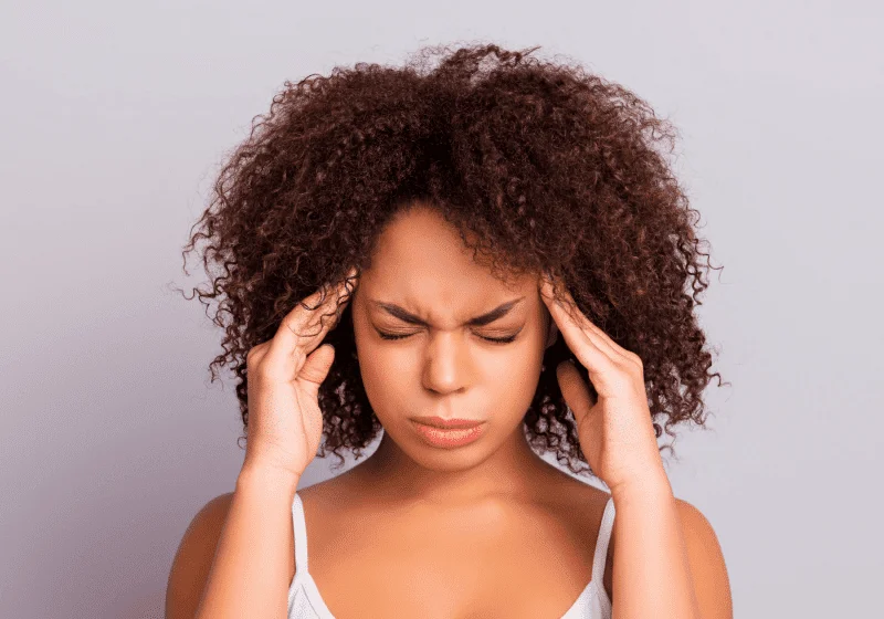black woman holding head hoping cannabis will help her migraine