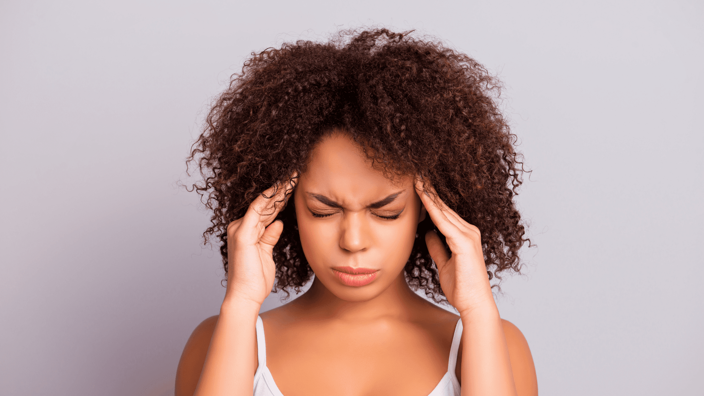 black woman holding head hoping cannabis will help her migraine