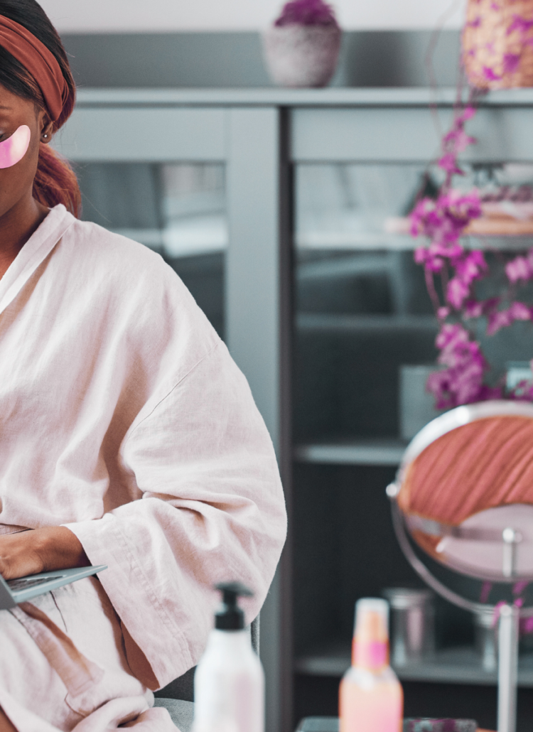 young black woman in spa robe typing on laptop doing self-care for healthier lifestyle