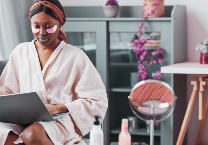 young black woman in spa robe typing on laptop doing self-care for healthier lifestyle