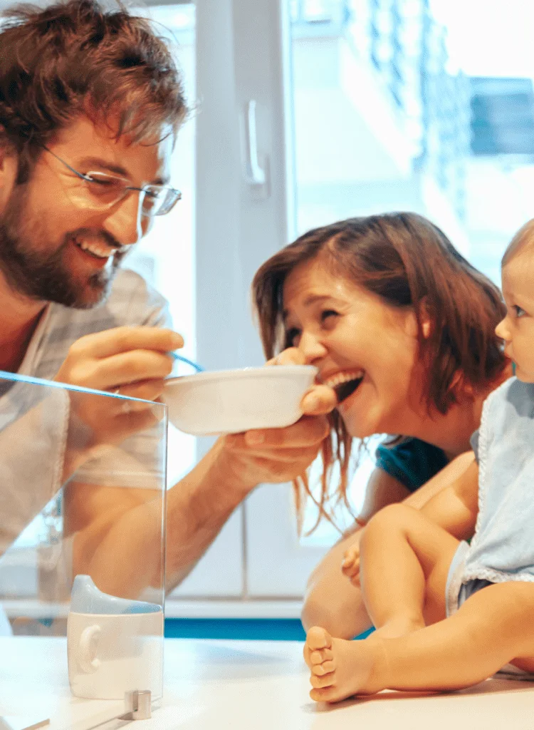 Happy new parents feeding their baby in a cafe