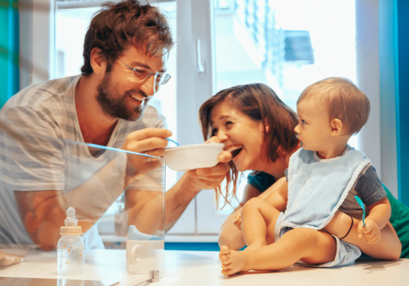 Happy new parents feeding their baby in a cafe