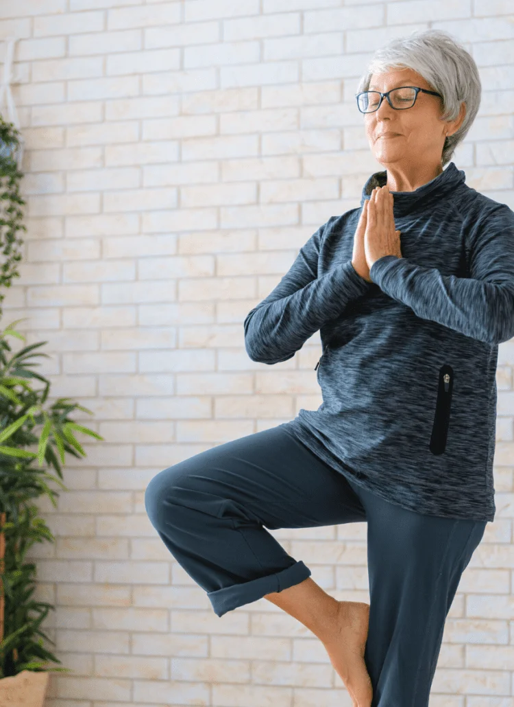 senior woman doing yoga tree pose after consuming cbd oil