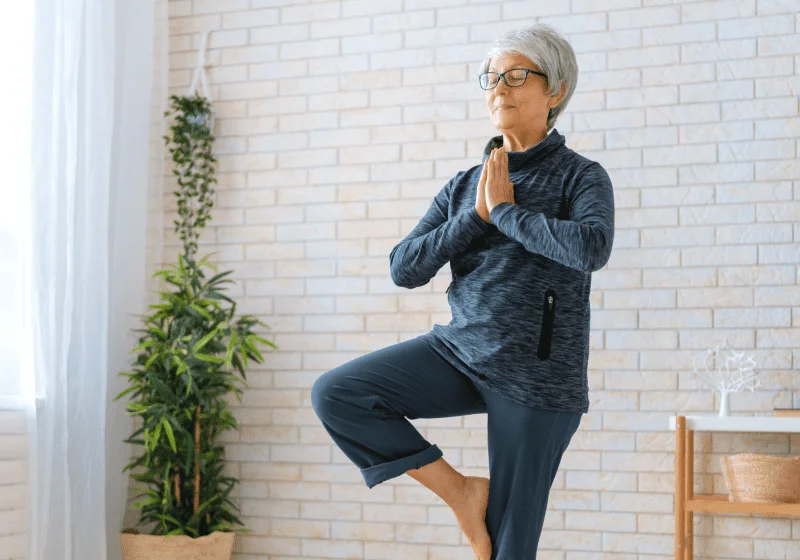 senior woman doing yoga tree pose after consuming cbd oil