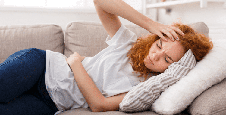 redhead woman on couch in stomach pain needs cbd oil