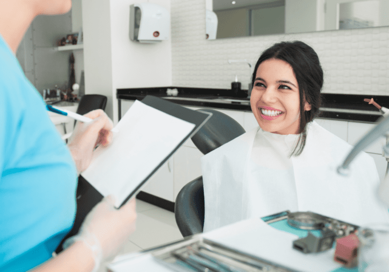 smiling young woman with black hair in dentist office learning about oral health