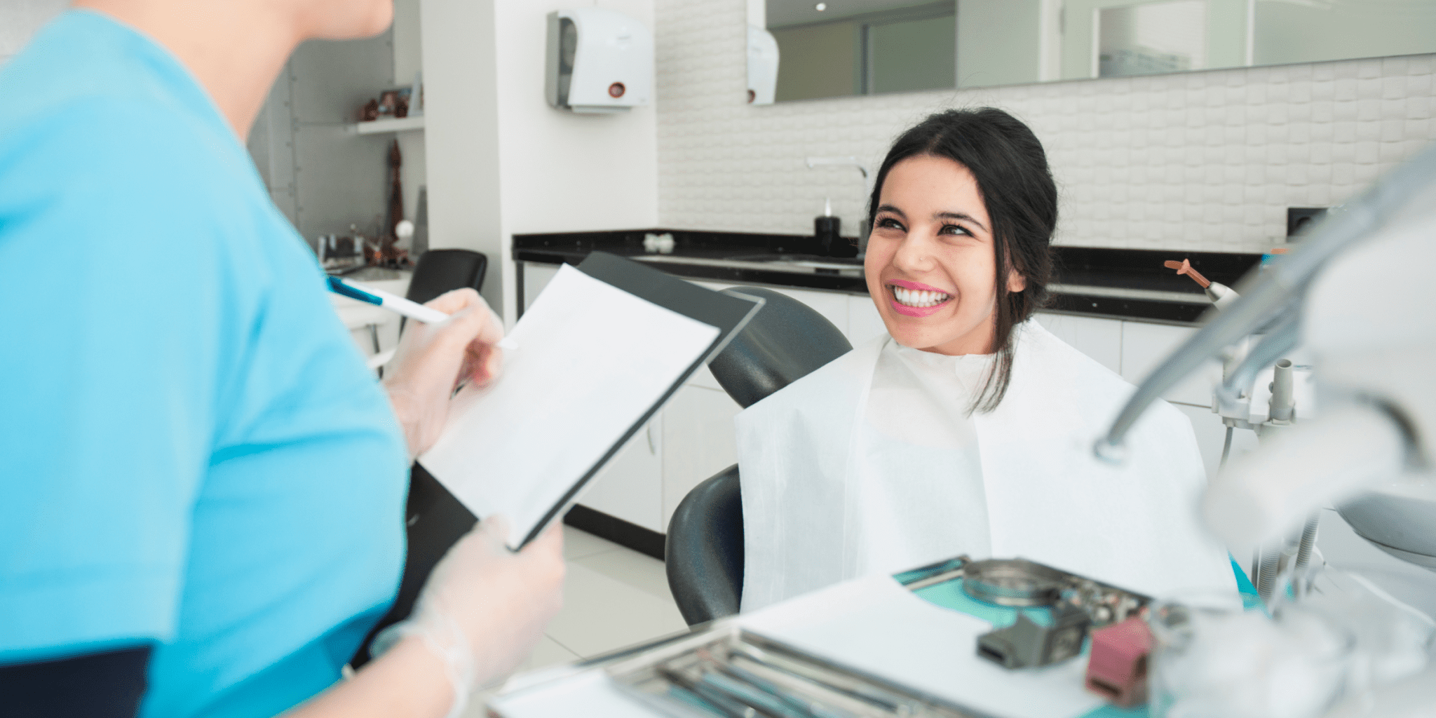 smiling young woman with black hair in dentist office learning about oral health