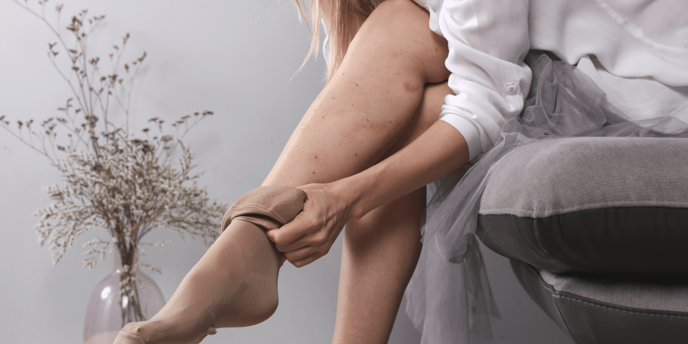 young woman with blond hair putting on compression stocking over leg with bruises