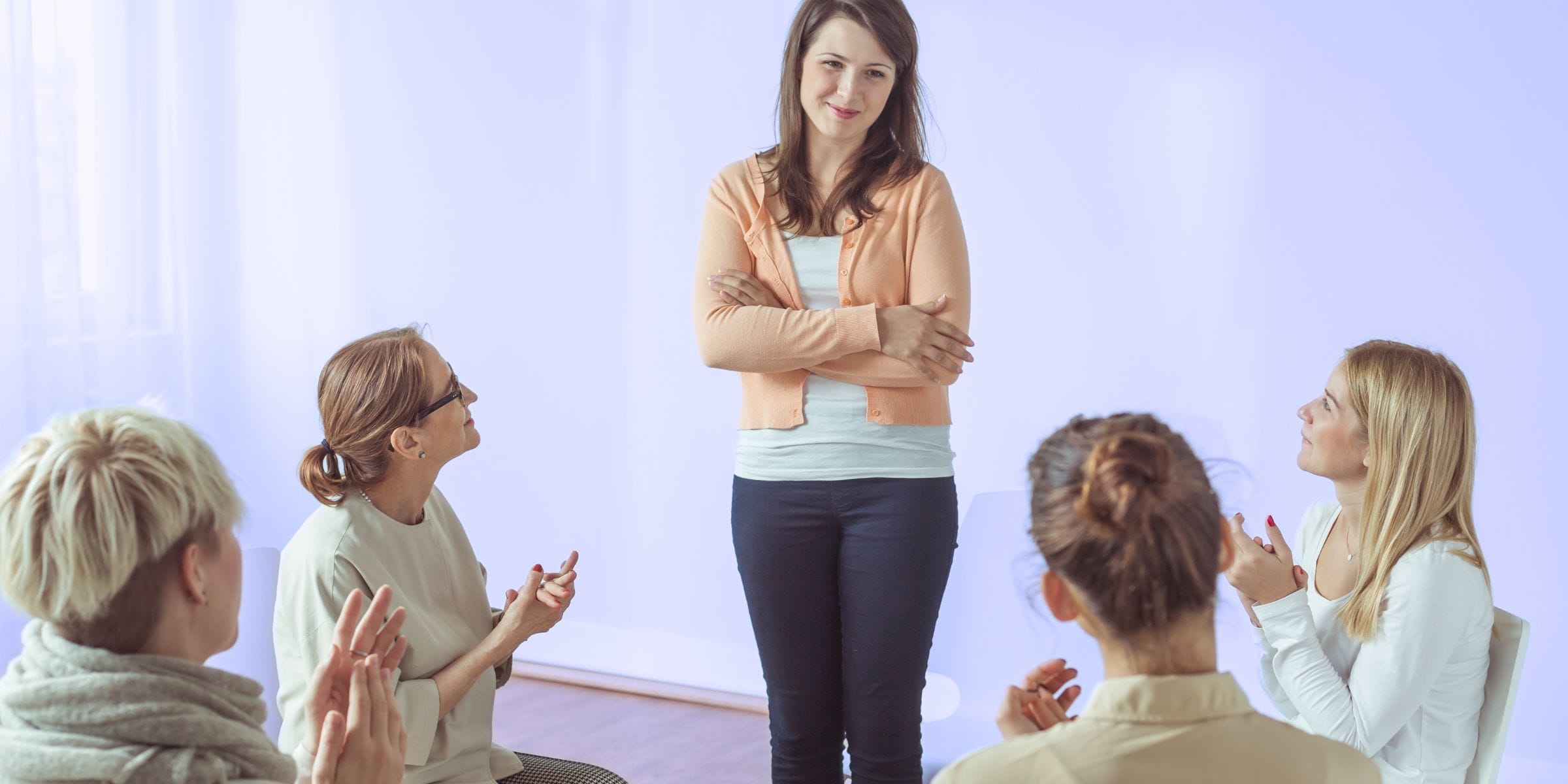 woman at AA meeting successful recovering addict getting praise in group therapy