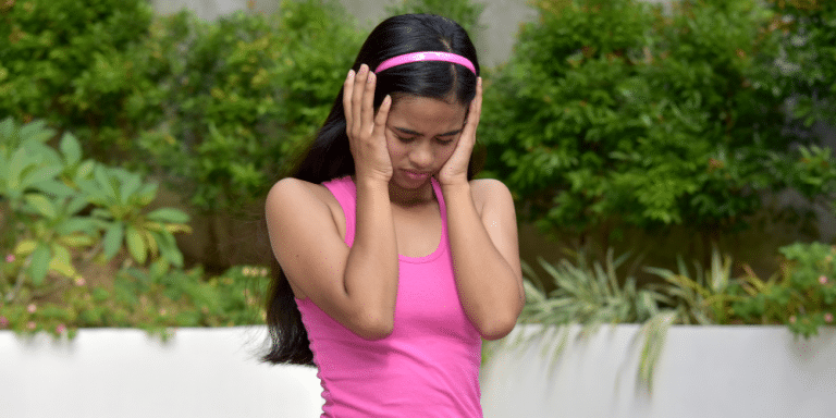 young asian girl holding hands over ears with anxiety