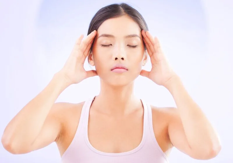 young asian woman with her eyes closed clearing her mind meditating