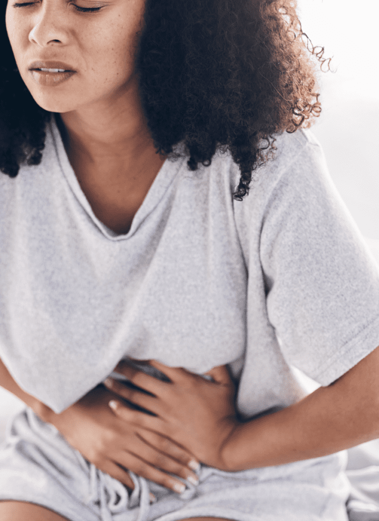 black woman holding stomach on bed leaky gut issues