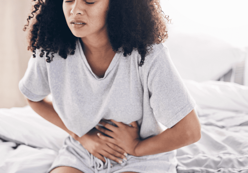 black woman holding stomach on bed leaky gut issues