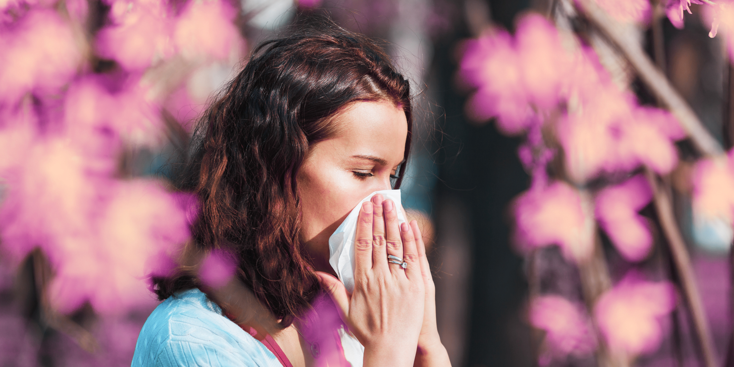 married woman outside with pollen allergies sneezing into tissue