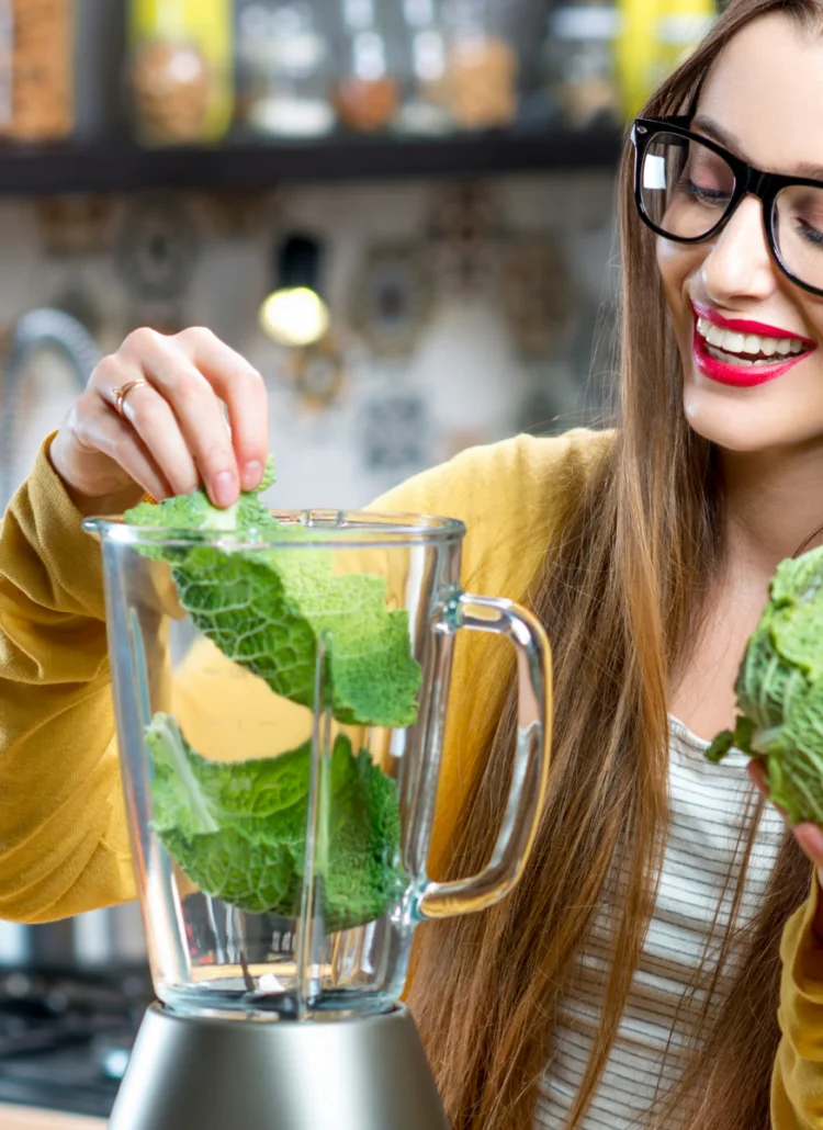 woman juicing lettuce in blender for healthy detox