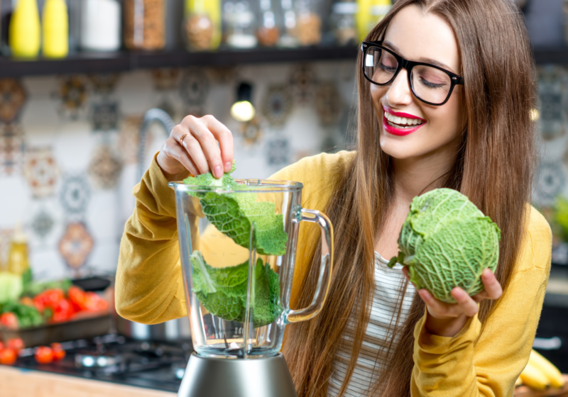 woman juicing lettuce in blender for healthy detox