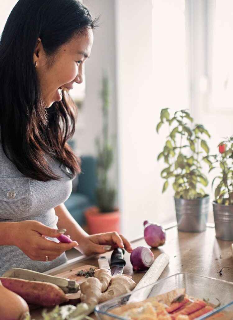 young asian woman preparing healthy food in the kitchen smiling with lots of energy