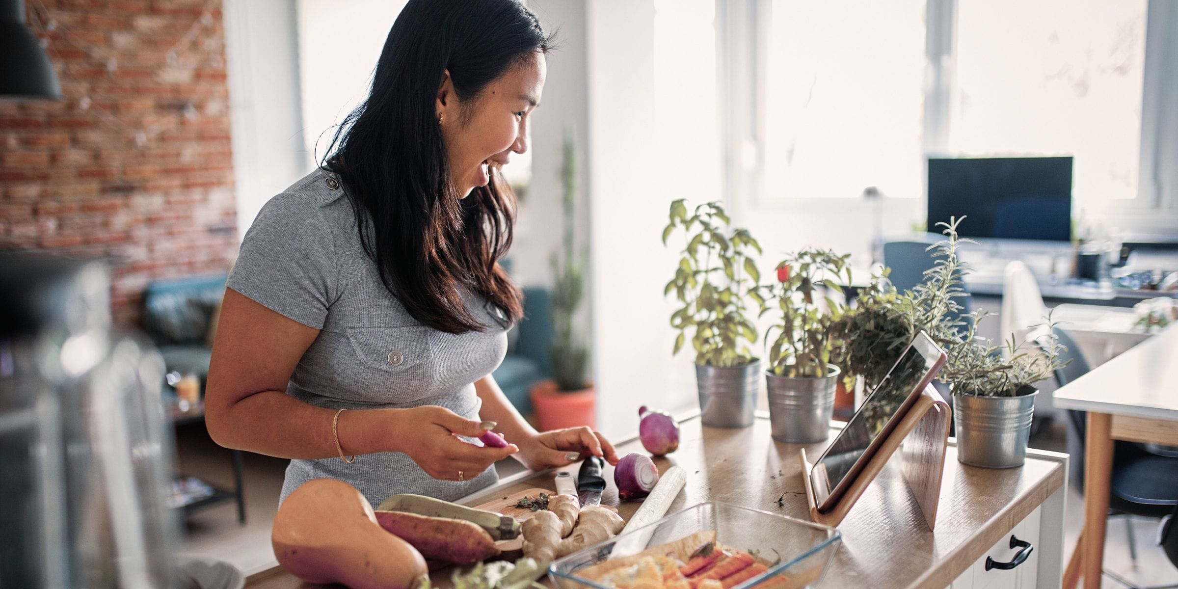 young asian woman preparing healthy food in the kitchen smiling with lots of energy