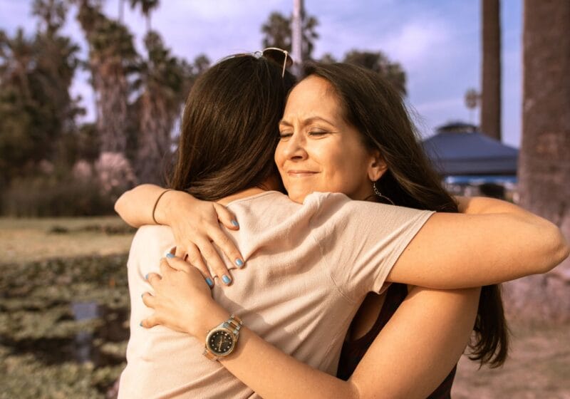 woman hugging friend with chronic health issues outside in park