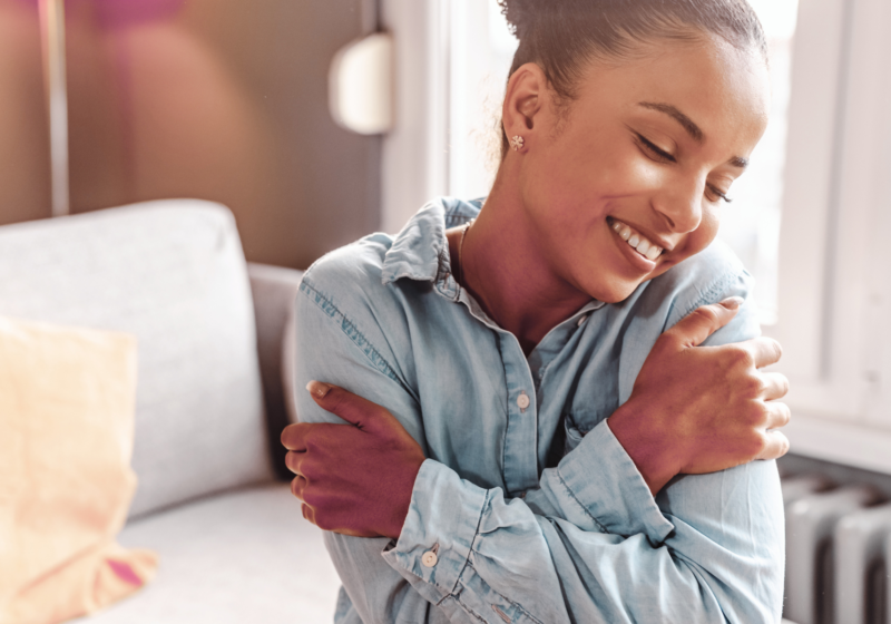 young black woman hugging herself practicing self-compassion