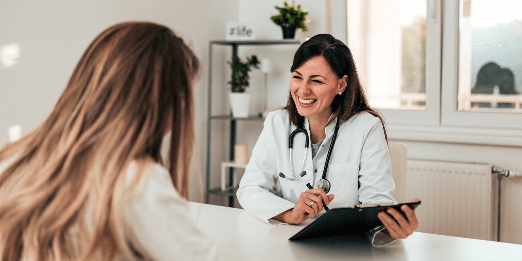 woman doctor smiling talking to satisfied female patient with long hair