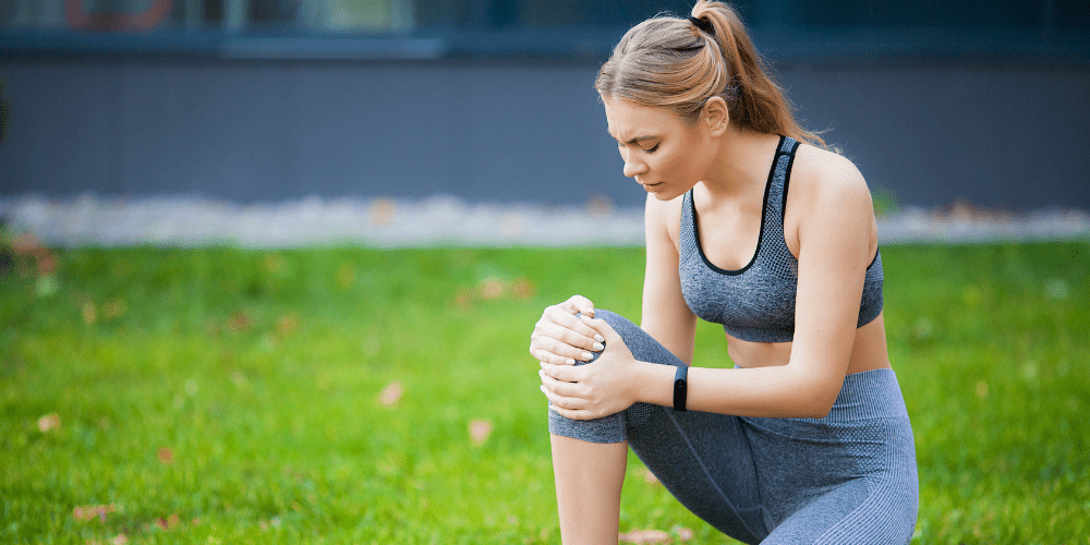 young woman kneeling with pain after running
