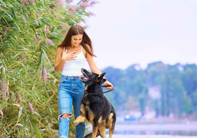 woman walking her german Shepard dog outside in park for self-care