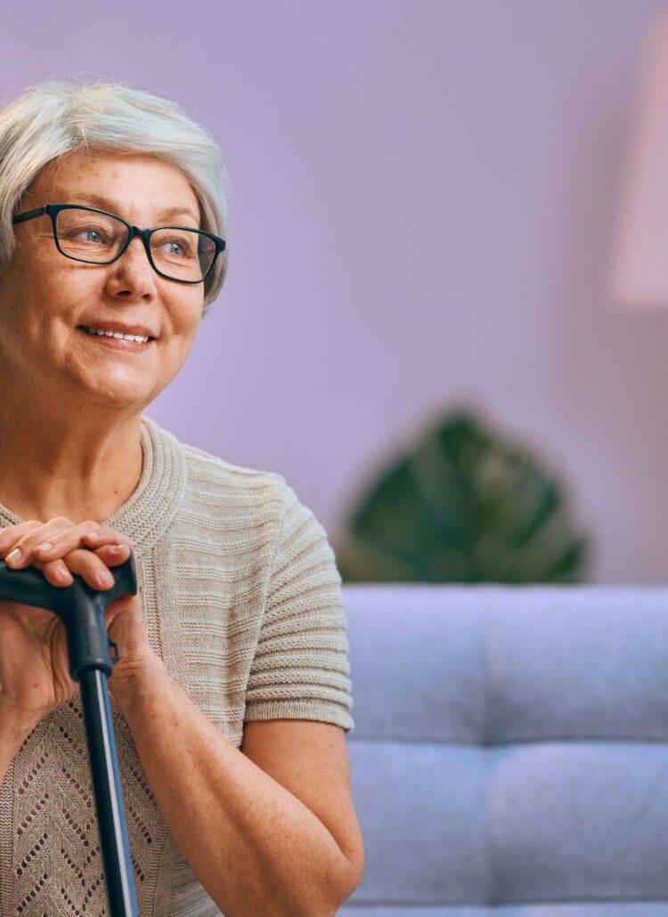 senior woman with arthritis pain resting with cane on couch
