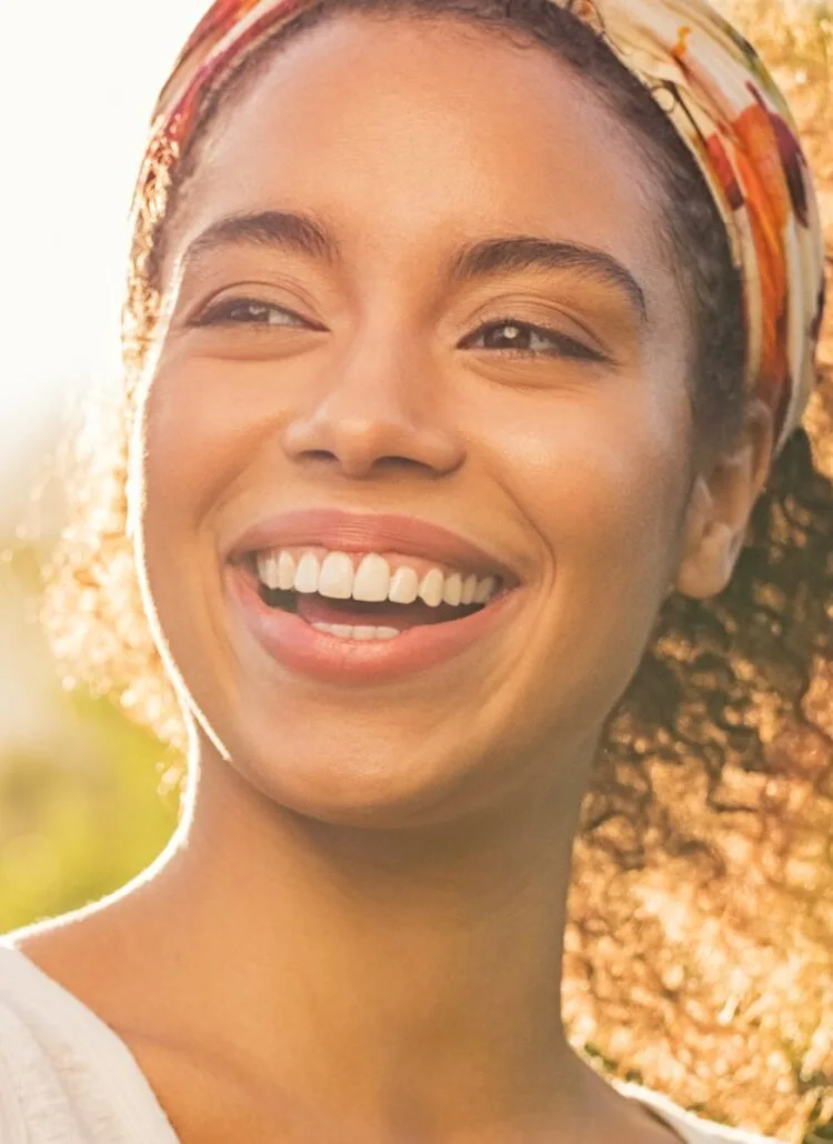 smiling black woman with perfectly straight teeth standing outside