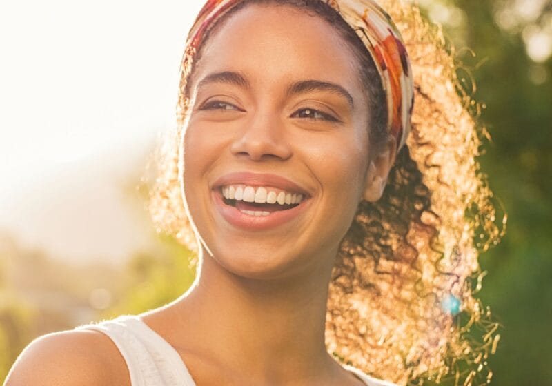 smiling black woman with perfectly straight teeth standing outside