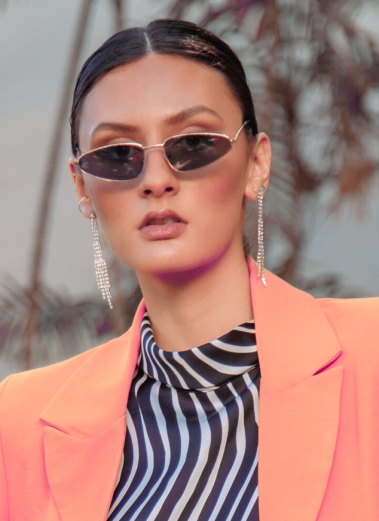 woman in orange blazer and zebra striped blouse and trendy sunglasses looking unforgettable before entering business networking event