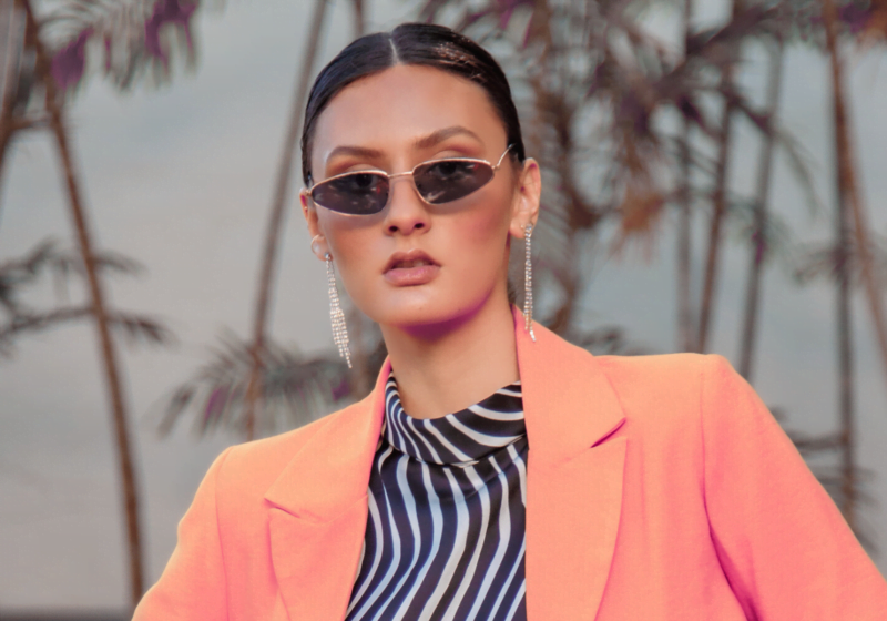 woman in orange blazer and zebra striped blouse and trendy sunglasses looking unforgettable before entering business networking event