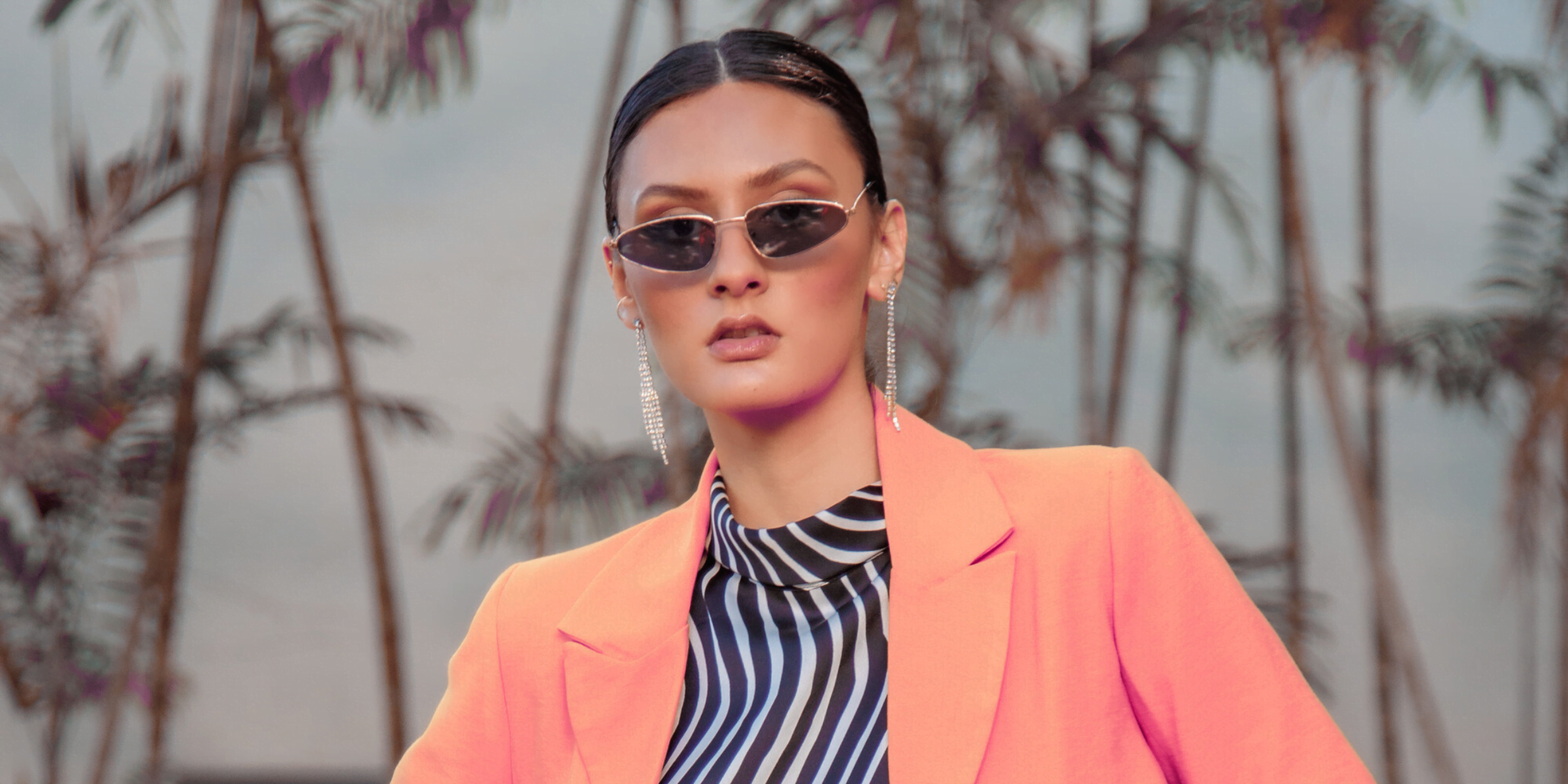 woman in orange blazer and zebra striped blouse and trendy sunglasses looking unforgettable before entering business networking event