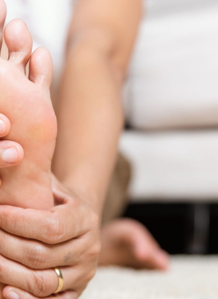 woman holding foot with peripheral neuropathy pain symptoms