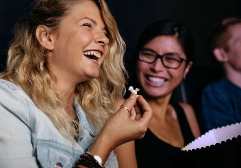 woman laughing in movie theater eating popcorn not stressed out