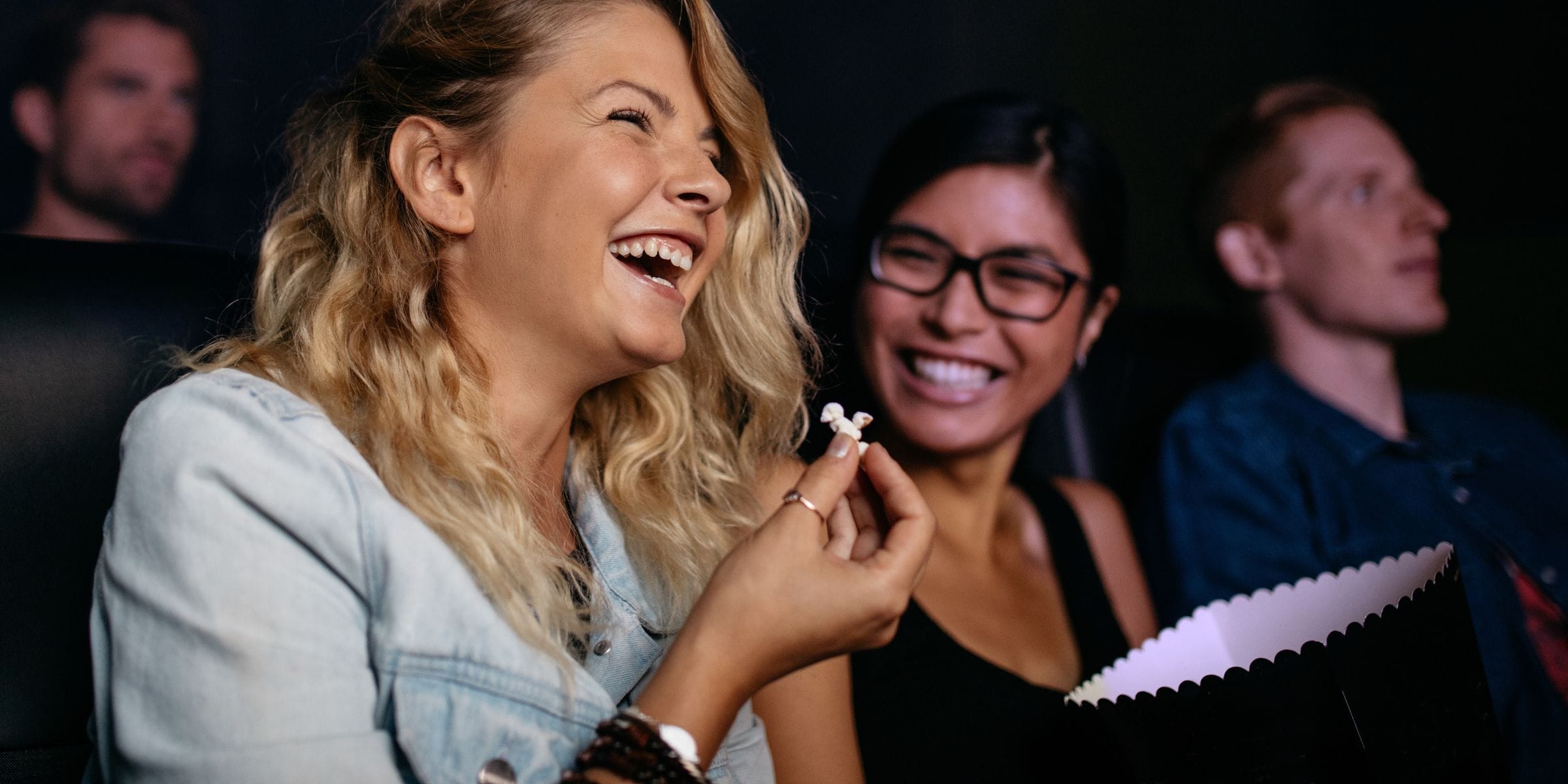 woman laughing in movie theater eating popcorn not stressed out