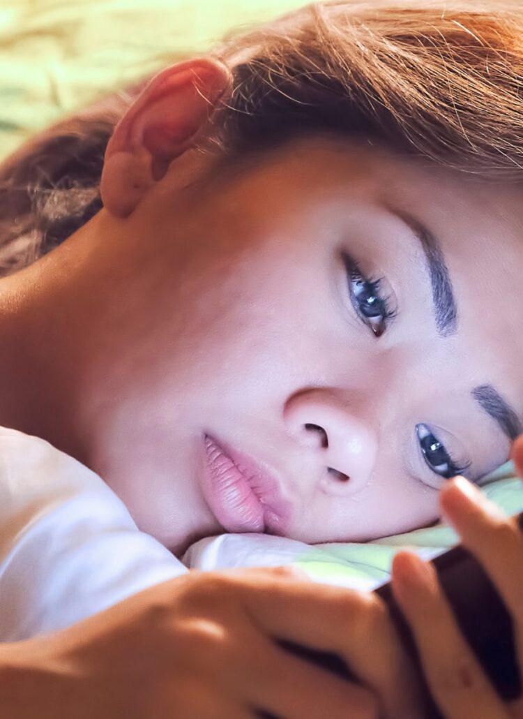 asian woman scrolling on instagram on phone before bed can't sleep and depressed