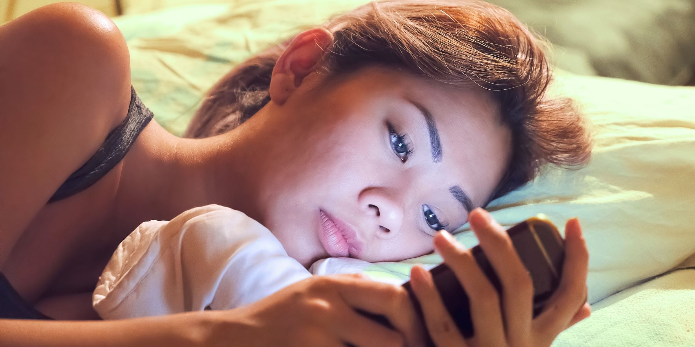 asian woman scrolling on instagram on phone before bed can't sleep and depressed