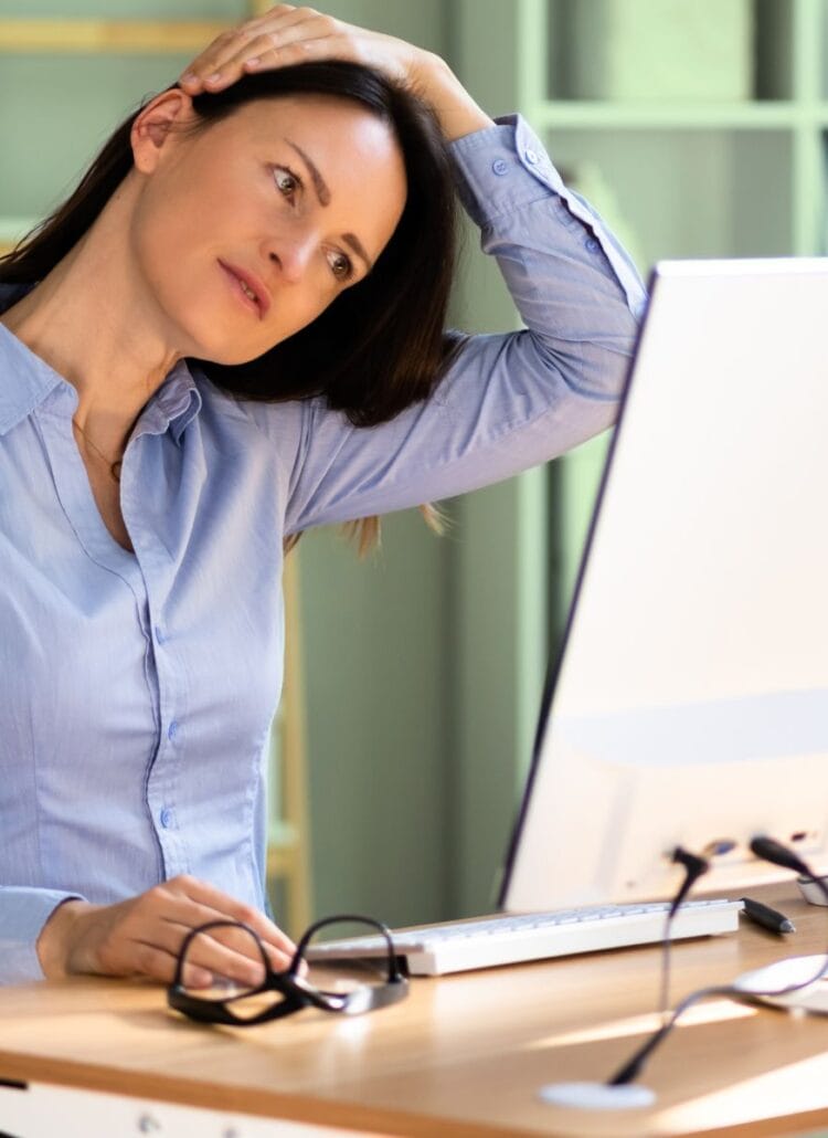 executive woman stretching neck while sitting at an office computer