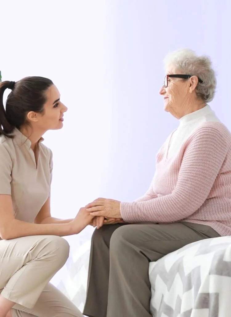 mother seated on bed worried talking to daughter about transitioning to a nursing home