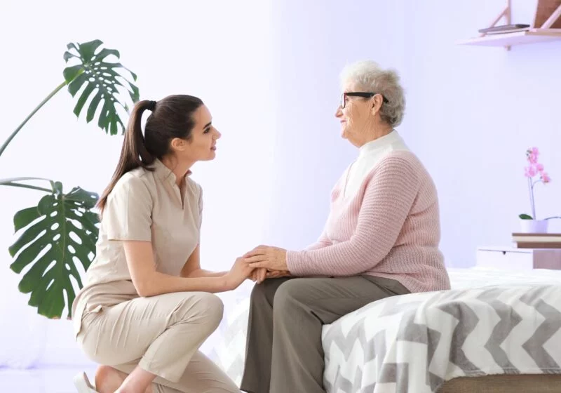 mother seated on bed worried talking to daughter about transitioning to a nursing home