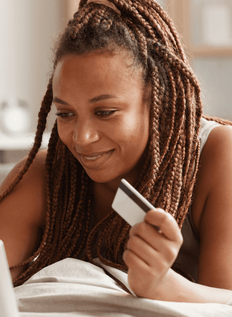 Black woman holding credit card buying medication online in her bed