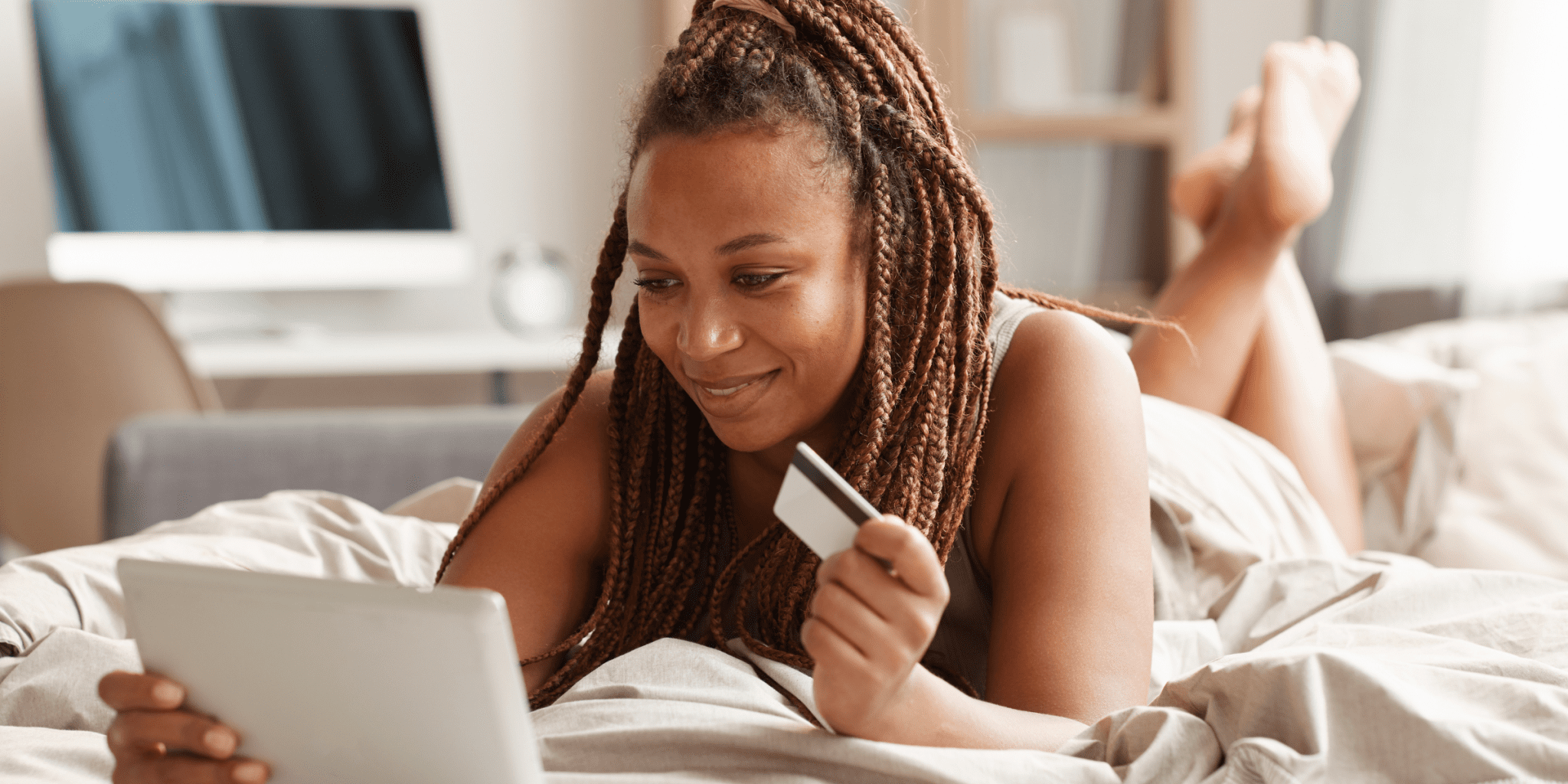 Black woman holding credit card buying medication online in her bed