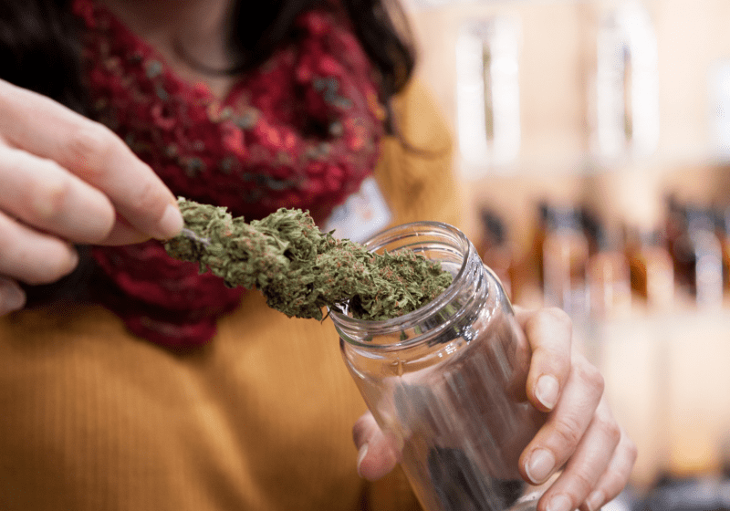 woman putting marijuana in storage container