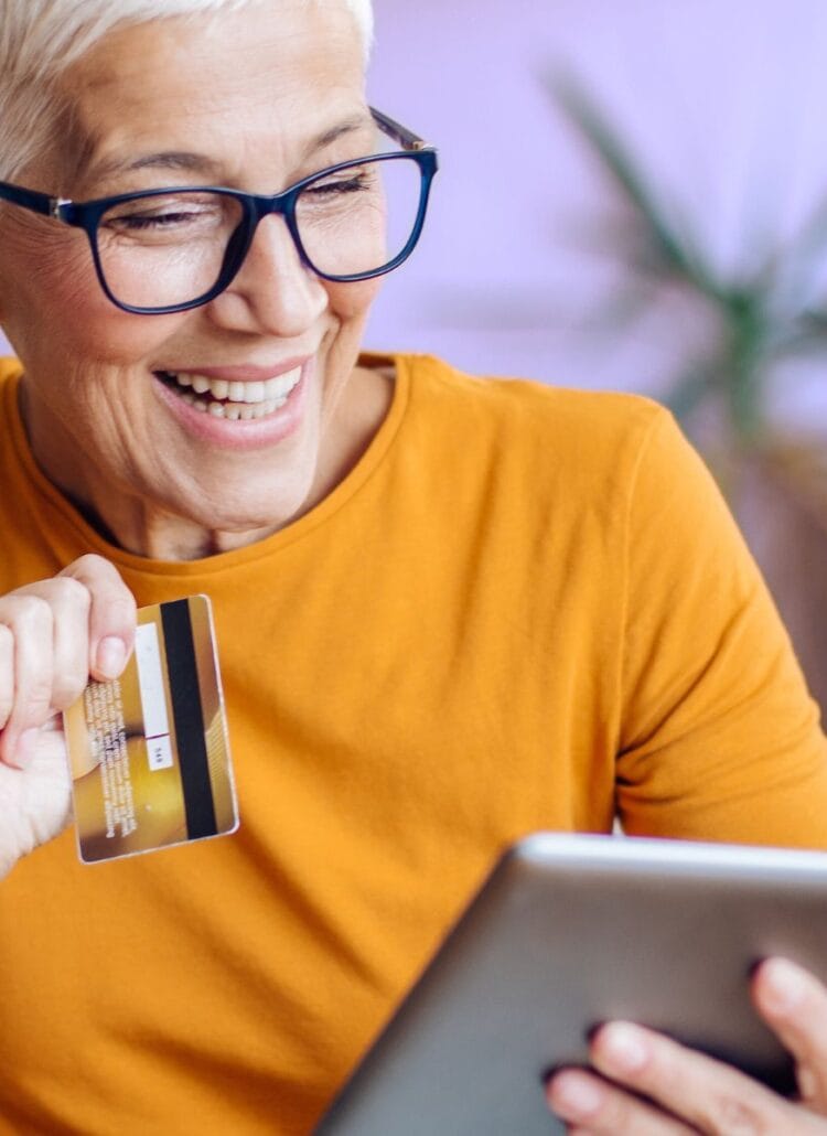 senior woman with glasses holding credit card shopping for cannabis online