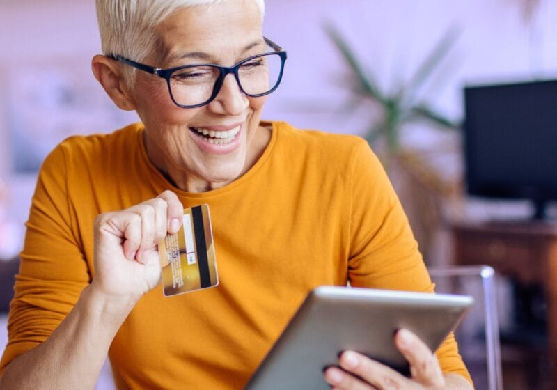 senior woman with glasses holding credit card shopping for cannabis online