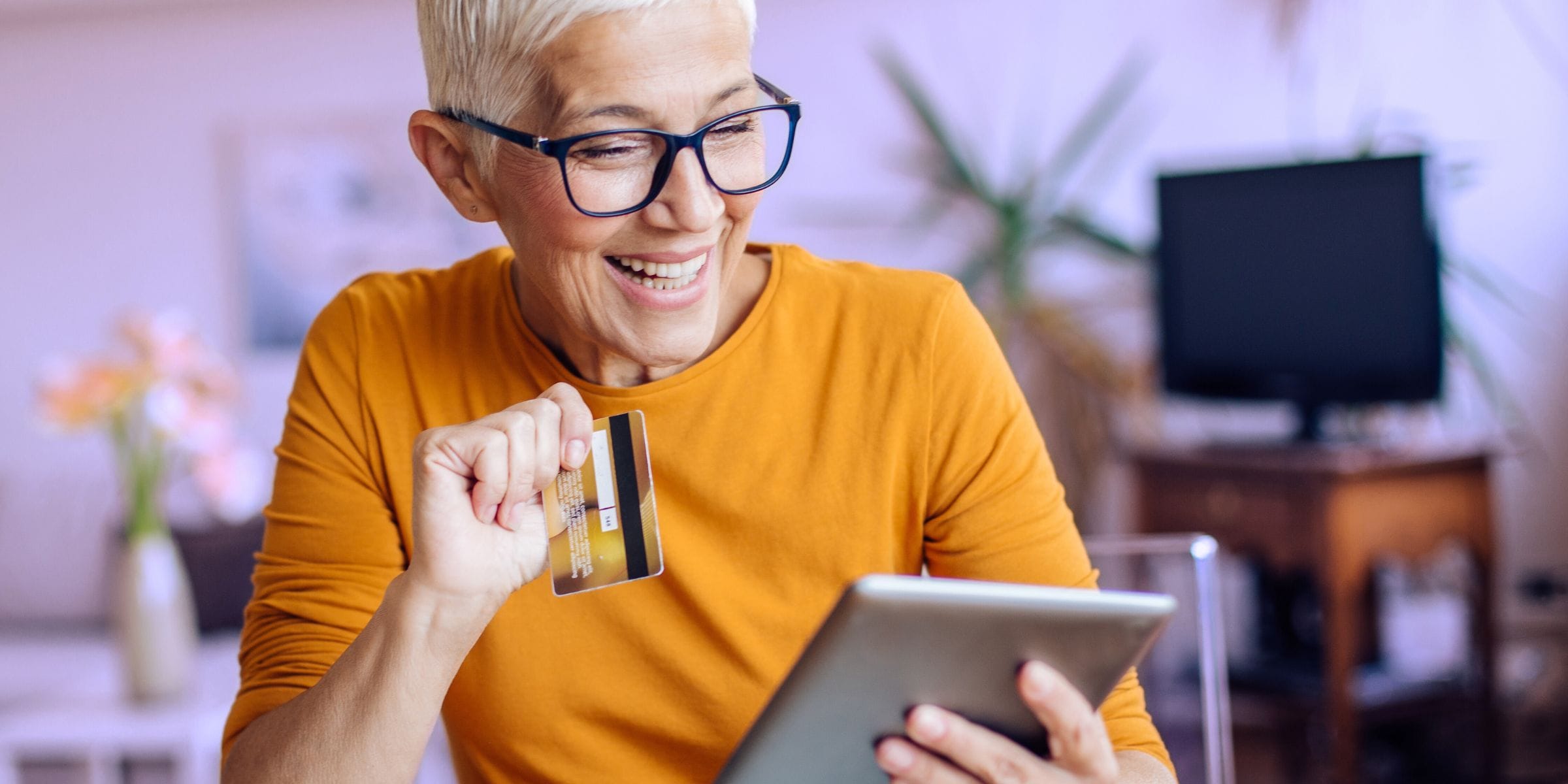 senior woman with glasses holding credit card shopping for cannabis online